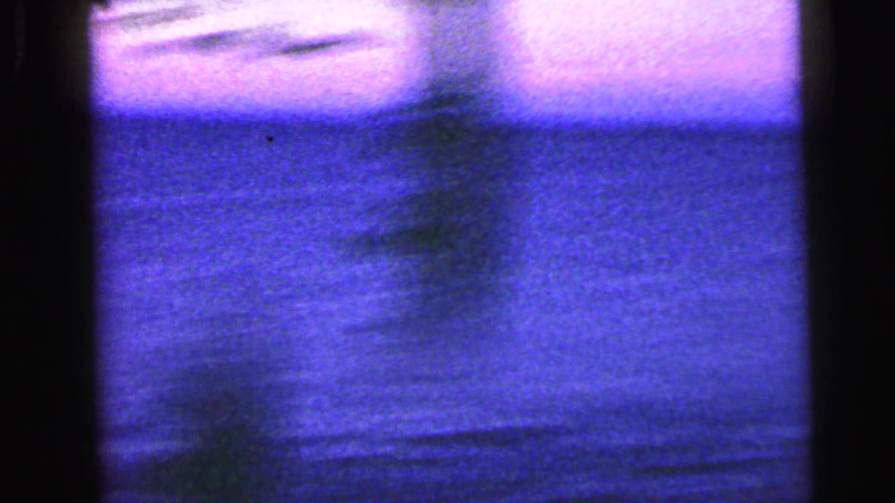 1964 Camden 8mm frame with blue-purple cast, soft water or sky texture, dark gate edges, and heavy grain.