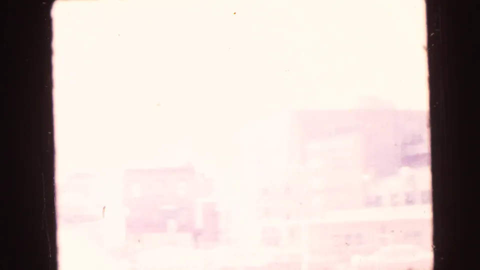 Overexposed 1964 Camden home-movie frame with faint shoreline forms, pale sky, dark film edge, and soft aged-film color.