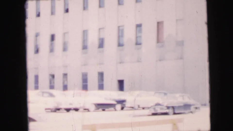 1964 Camden exterior showing a pale multi-story building and several mid-century cars parked along the curb.