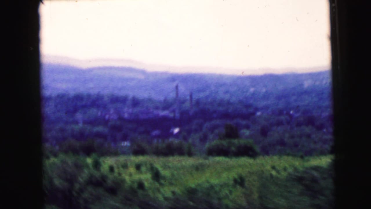 Moving 8mm view of wooded hills and green foreground, associated by metadata with Camden, New Jersey in 1964.
