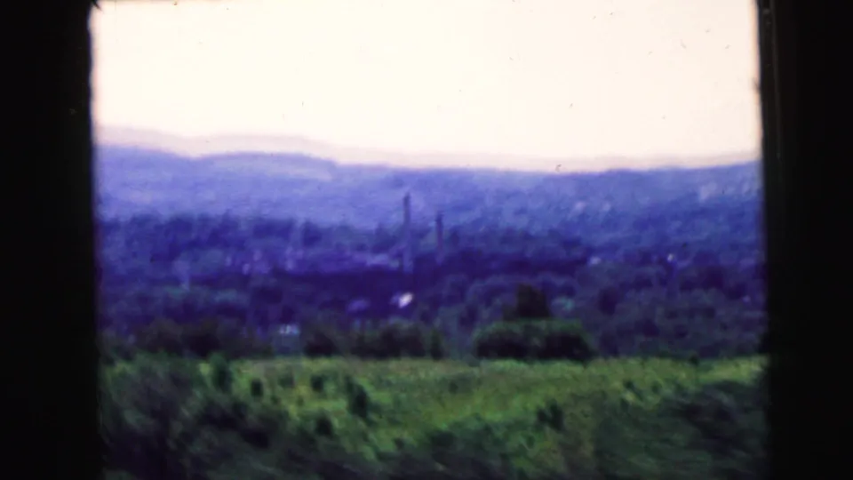 Moving 8mm view of wooded hills and green foreground, associated by metadata with Camden, New Jersey in 1964.