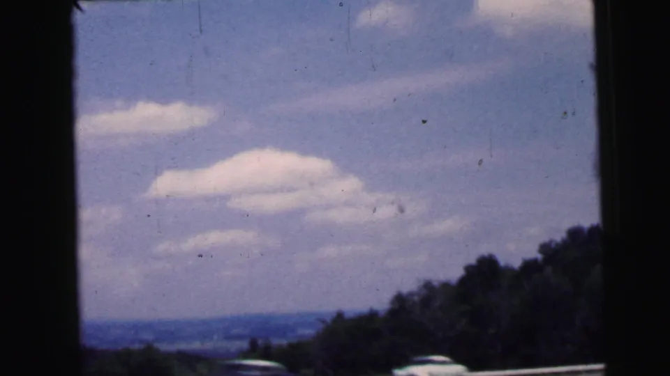 A broad sky with soft clouds and a distant landscape, likely filmed from a vehicle in Camden, New Jersey in 1964.