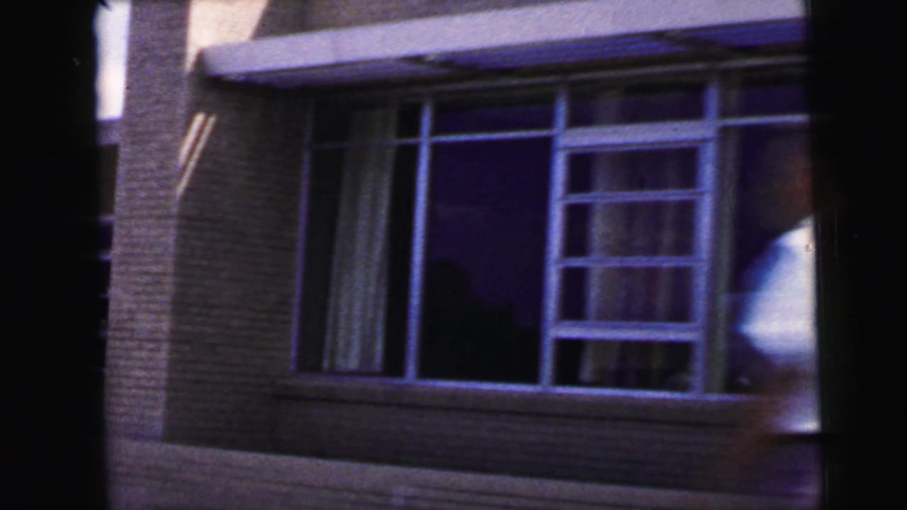 Large-window brick building glimpsed from 1960s 8mm travel footage, likely in the Camden, New Jersey clip context.