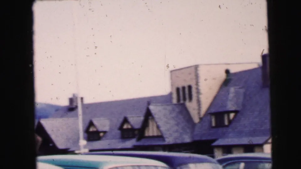 1964 Camden, New Jersey frame showing snow, parked cars, dormers, a chimney, and a steep-roofed building.