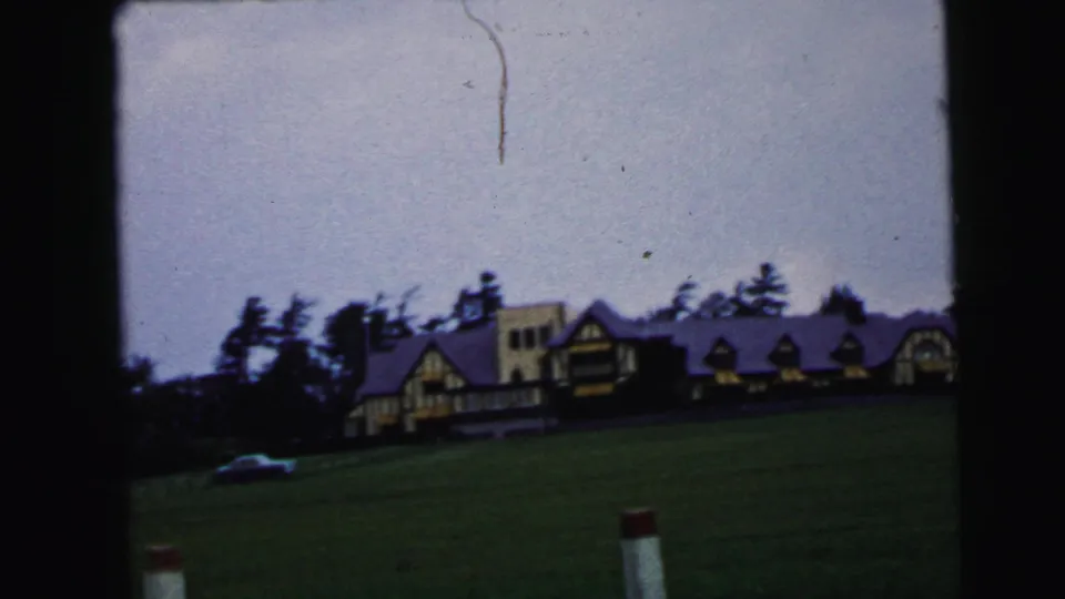End frame of the 1964 Camden storm view, with a small car near the distant building under a pale overcast sky.