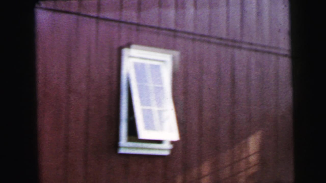 Red wood wall with a white-framed window propped open outward.
