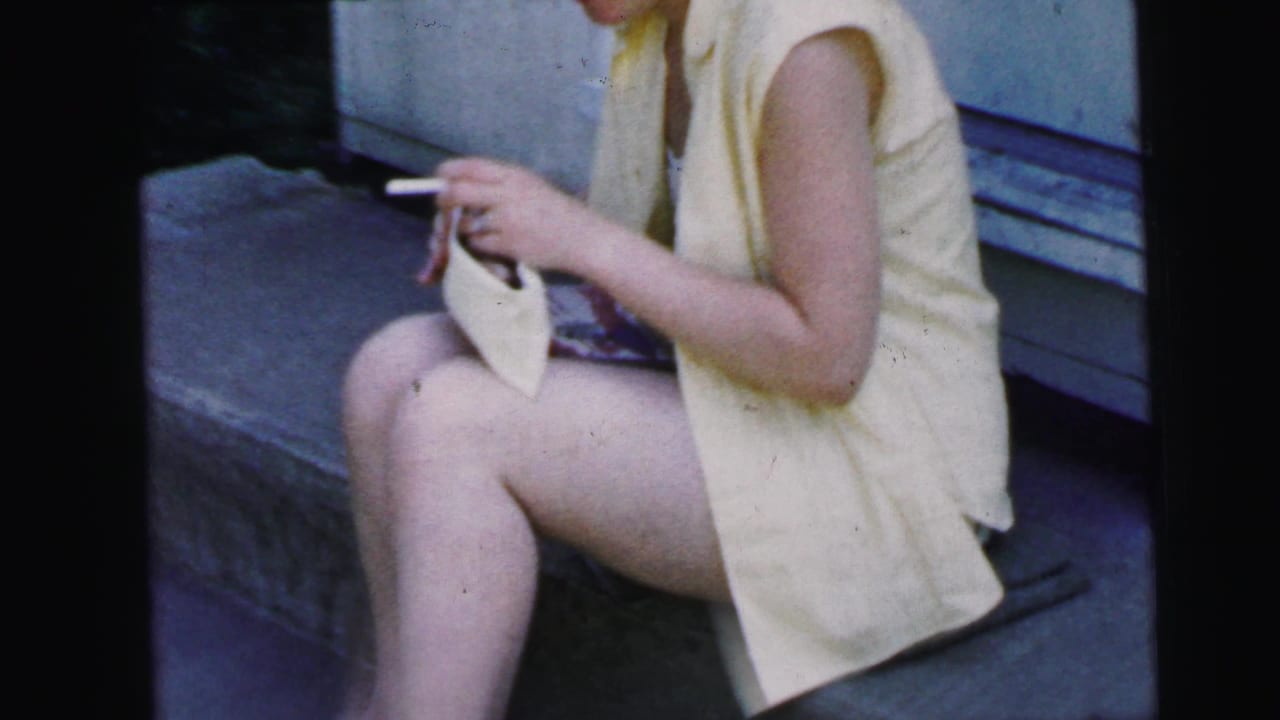 Closer view of the seated woman holding a cigarette and small notebook on the steps.