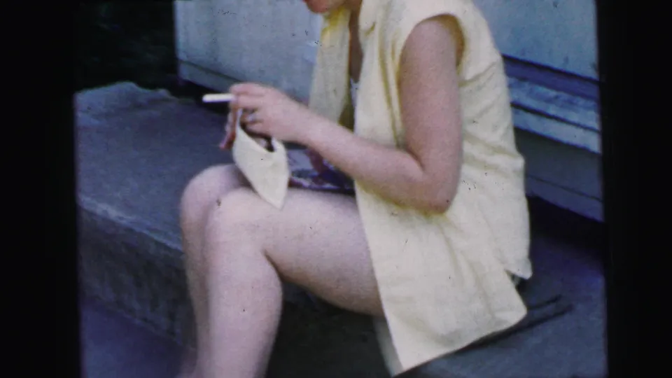 Closer 1964 Camden view of the woman on stone steps, holding a cigarette while working with a small notebook.