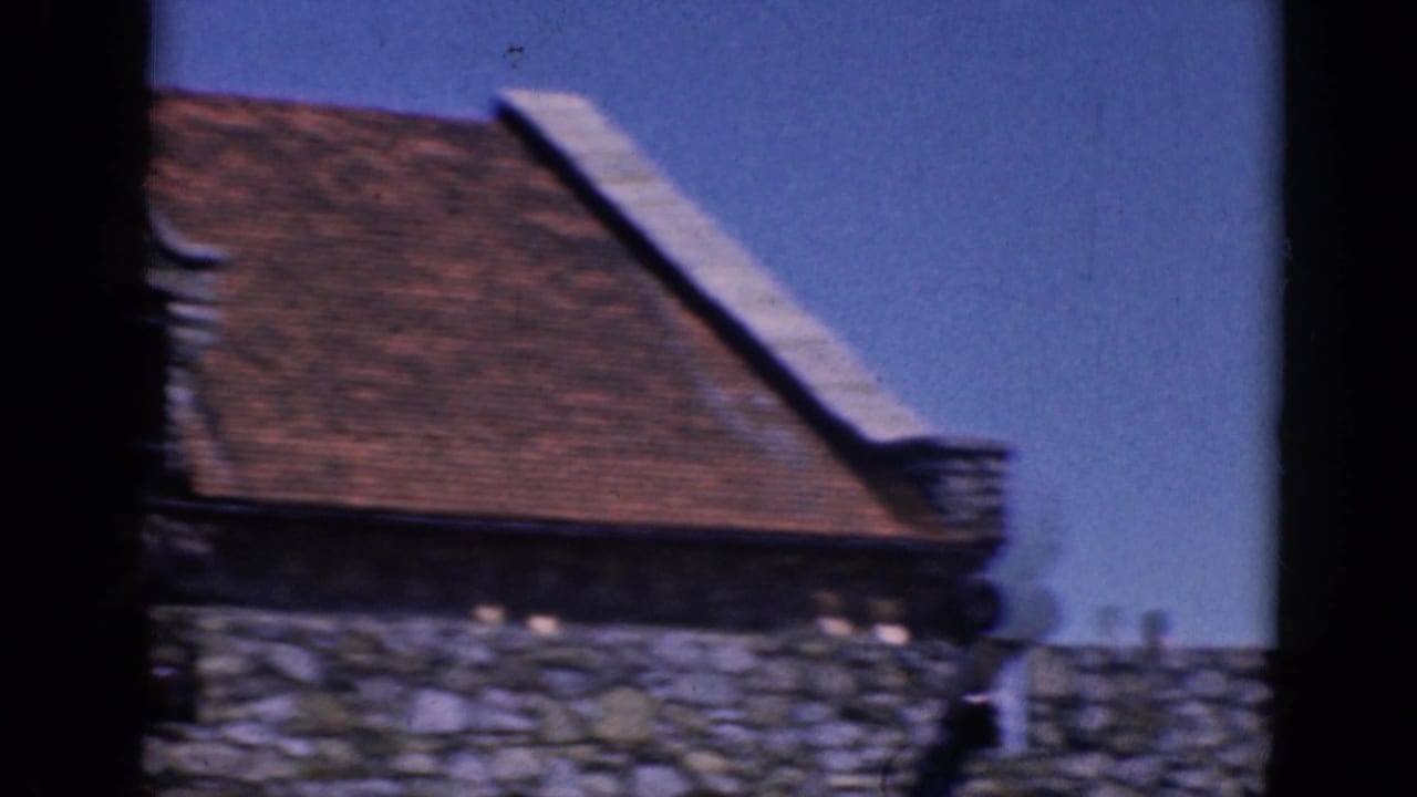 Charlestown, North Carolina roofline in 1964 home-movie footage, with stonework and a small distant person near the wall.