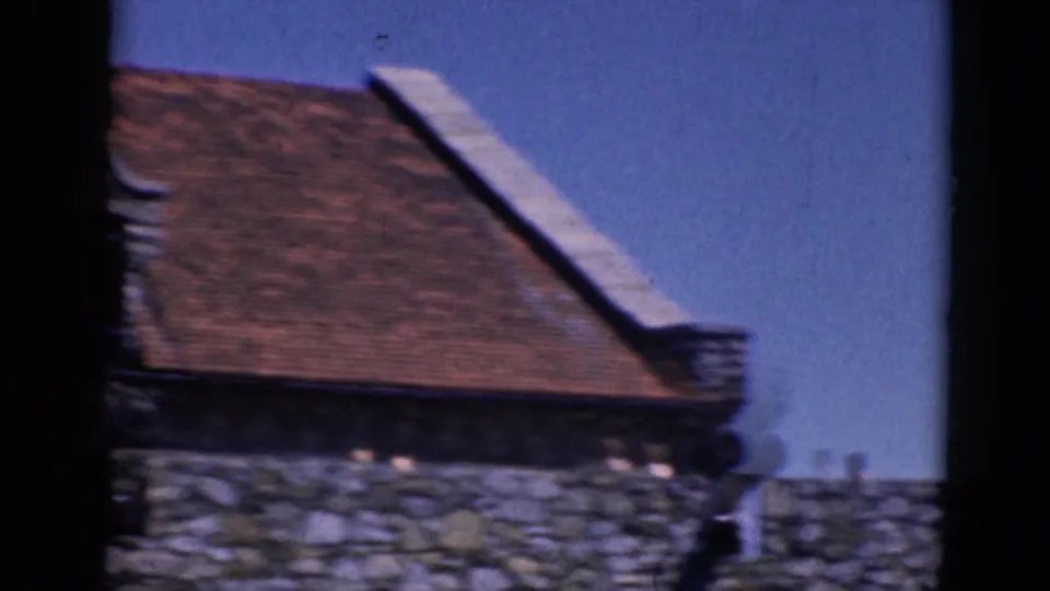 Charlestown, North Carolina roofline in 1964 home-movie footage, with stonework and a small distant person near the wall.