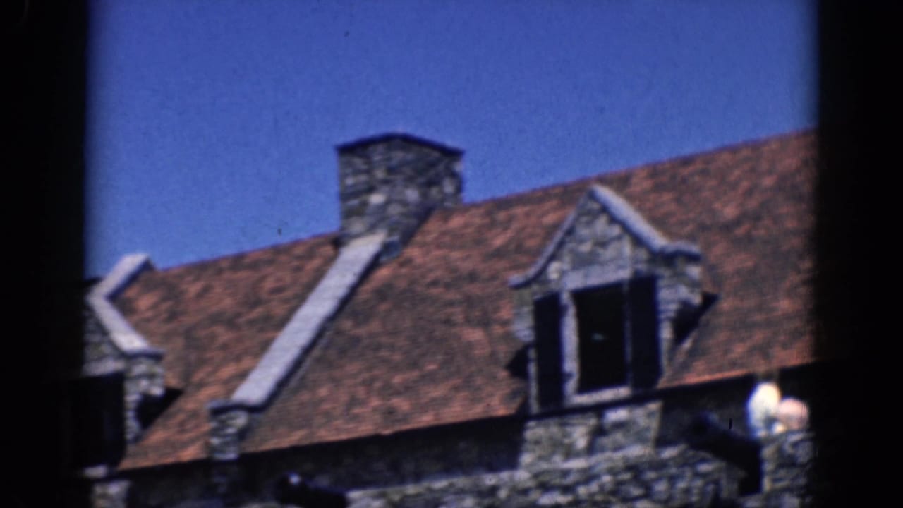 Charlestown, North Carolina home-movie frame showing a red roof, chimney, dormer window and stone masonry wall.