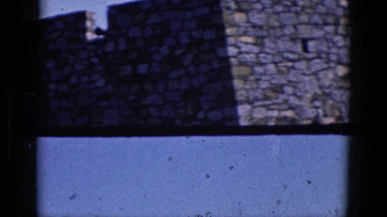 1964 Charlestown, North Carolina home-movie frame showing shadowed stonework, battlements, and open blue sky through dark framing.