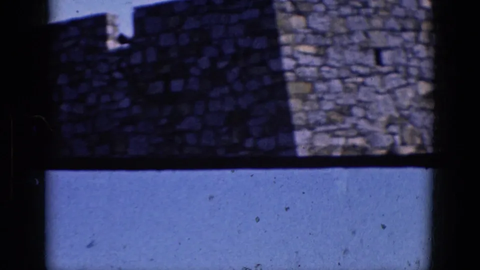 1964 Charlestown, North Carolina home-movie frame showing shadowed stonework, battlements, and open blue sky through dark framing.