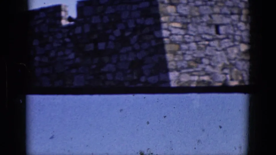 1964 8mm view of a stone building top in Charlestown, North Carolina, with crenellations, small openings, and visible film grain.