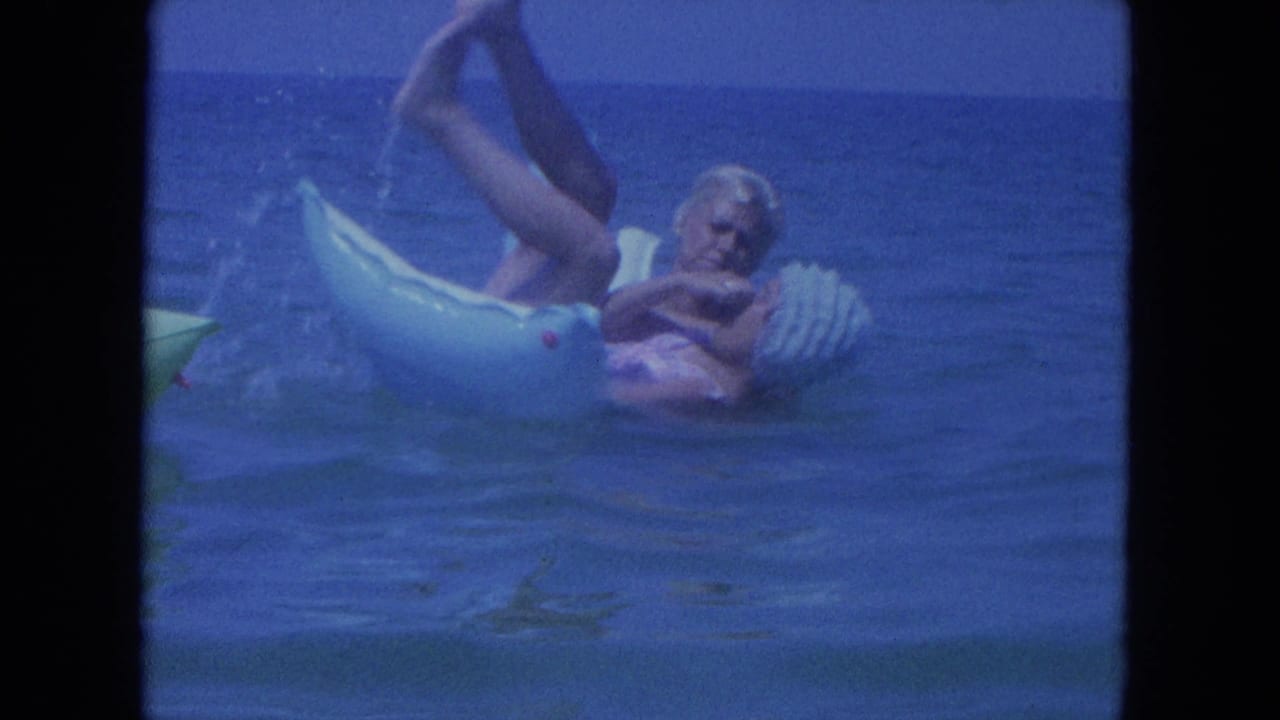 The woman reclines playfully on the light blue ring in Clearwater ocean water, with one leg lifted and small splashes beside the float.