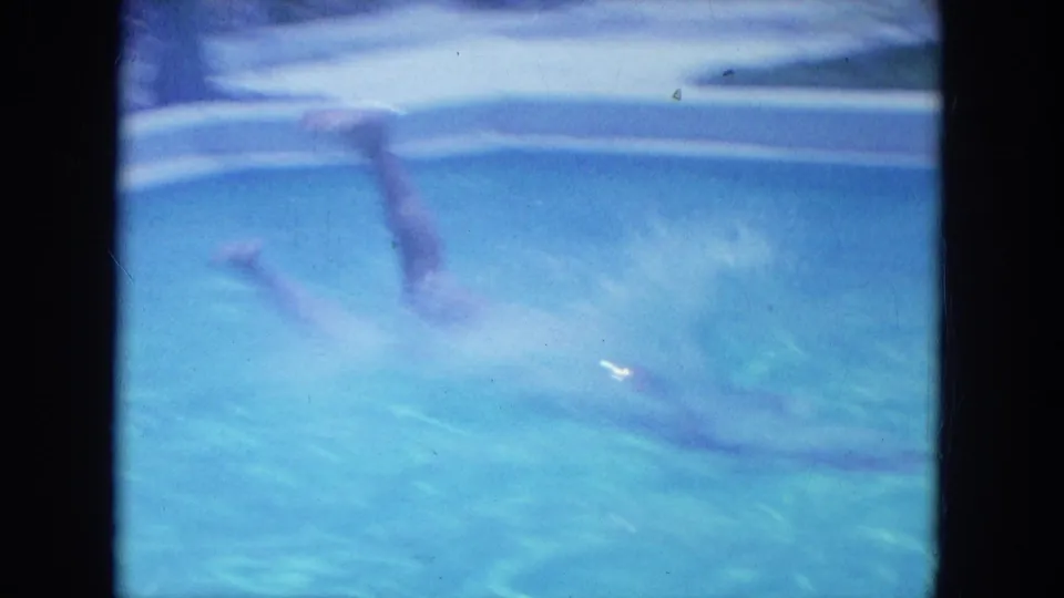 A blue 8mm frame shows the diver underwater after entering the motel pool, with motion blur and rippled light across the water.