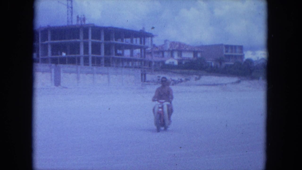 1964 Clearwater beach frame with a scooter rider approaching the camera and unfinished beachfront construction visible behind him.