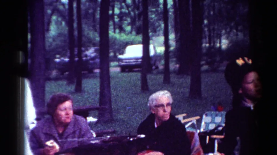 Final frame shows seated adults at a 1964 Cleveland park gathering, with trees and a parked car in the background.