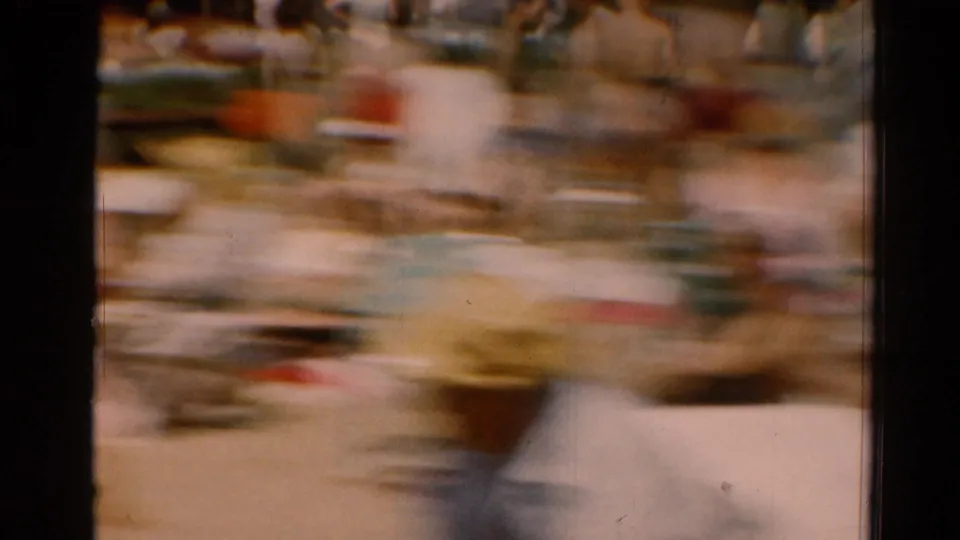 1964 Cleveland beach frame with motion blur across a crowded sandy area, showing swimsuit-clad figures and beach seating.