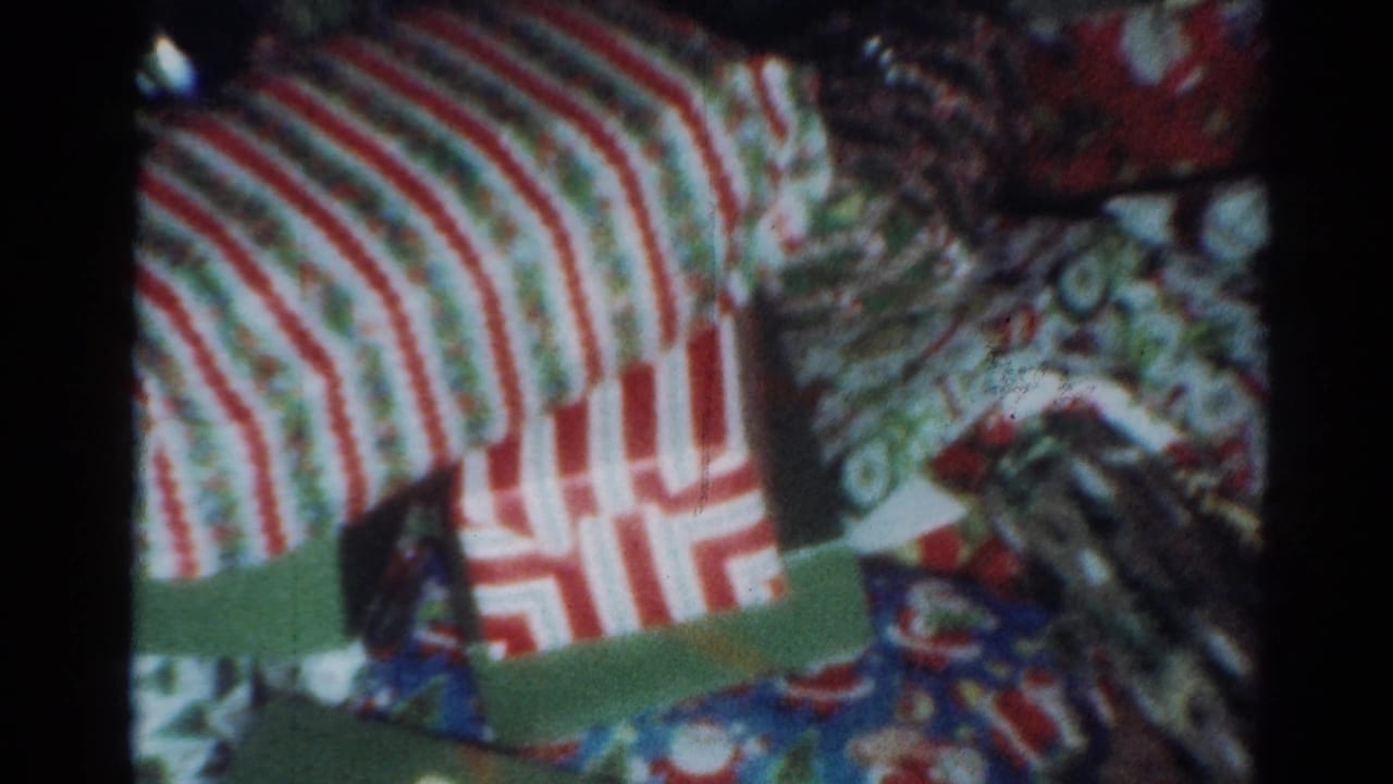 Wrapped Christmas gifts in a Cleveland 1964 home-movie scene, including striped paper and colorful holiday wrapping.