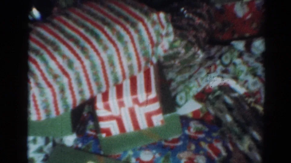 Wrapped Christmas gifts in a Cleveland 1964 home-movie scene, including striped paper and colorful holiday wrapping.