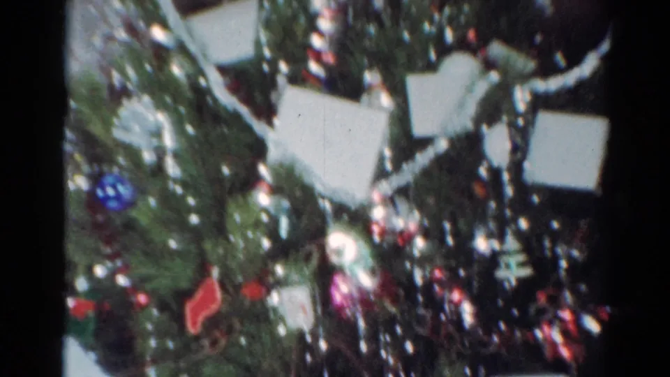 Close 1964 Cleveland holiday frame with evergreen branches, reflective tinsel, red and blue ornaments, and small white cards tucked into the tree.