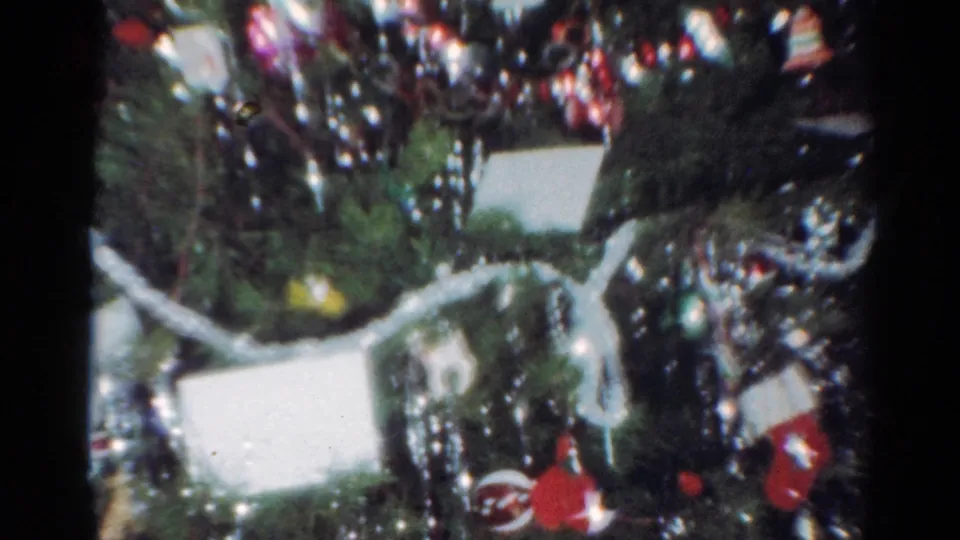 End frame from the 1964 Cleveland home movie showing a decorated Christmas tree with tinsel, red ornaments, white cards, and soft 8mm color.
