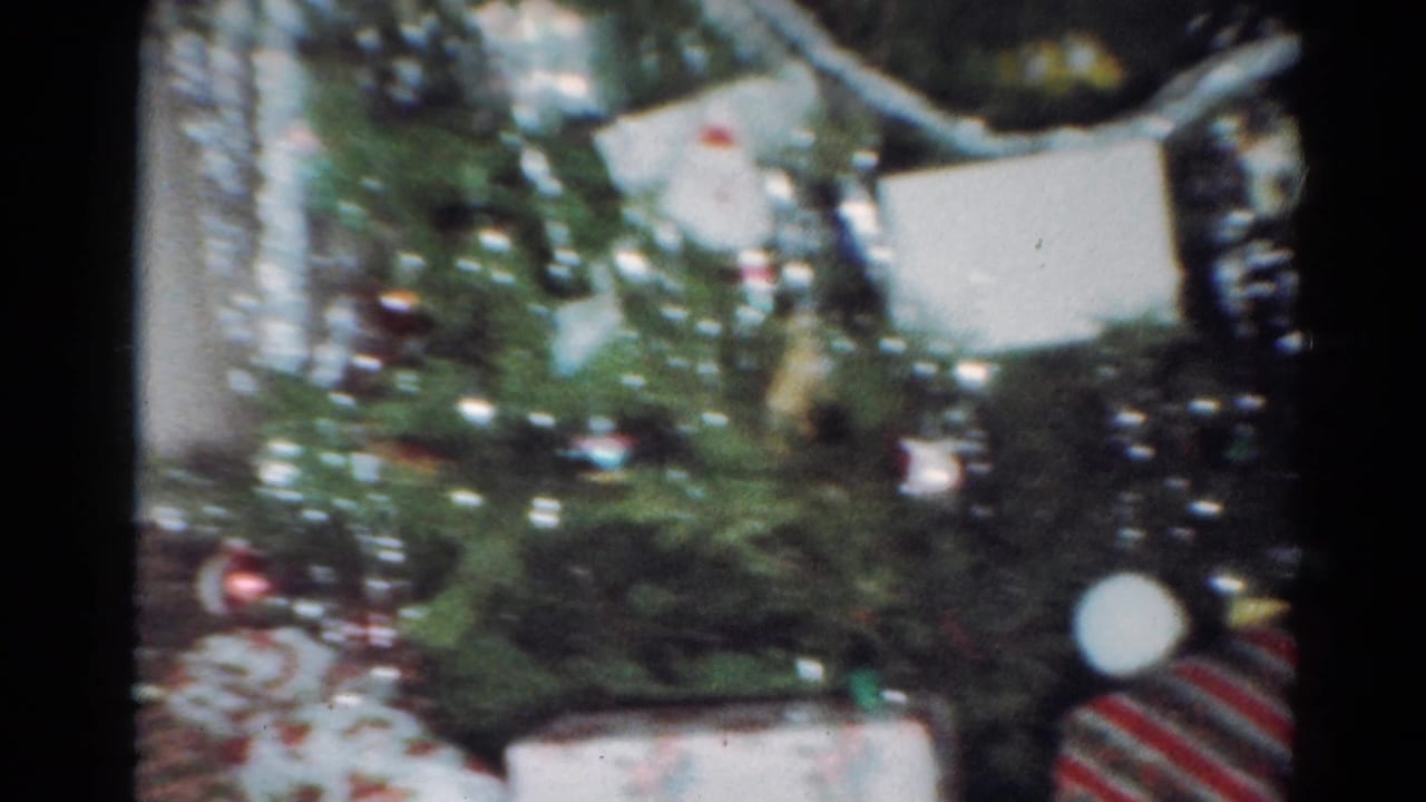 1964 Cleveland interior frame with a Christmas tree, ornaments, white ribbon, wrapped presents, and a striped red-and-white gift box.