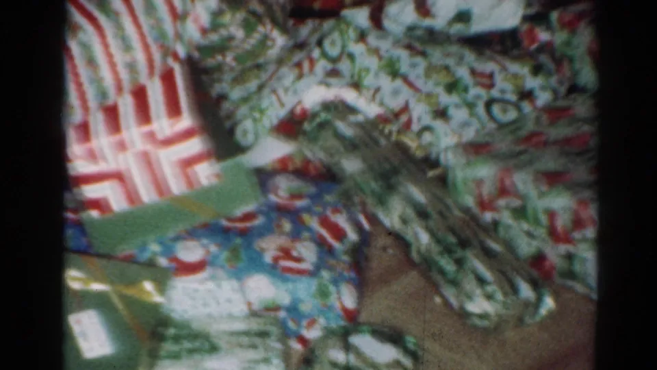 1964 Cleveland home-movie frame with several unopened gifts, including striped wrapping and ribboned packages.