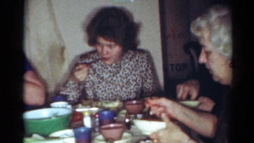 Two adult women eat at a table in a Cleveland private interior, with a green serving bowl and cups visible in the foreground.