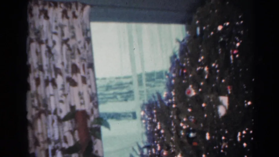 A 1964 Cleveland holiday frame holds on the decorated tree, window, and patterned curtains after the present shifts away.