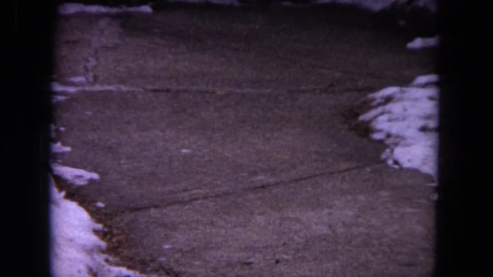 Evanston 1964 home-movie frame showing a winter walkway with patches of snow and no people visible.