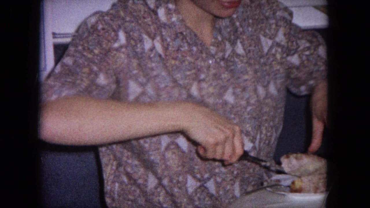 Young woman in a patterned shirt carving meat on a plate in a kitchen.