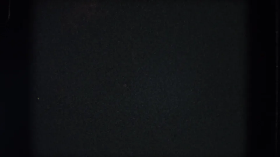 1964 8mm home-movie frame from Evanston showing mostly dark film exposure with a narrow partial view of grass near the bottom.