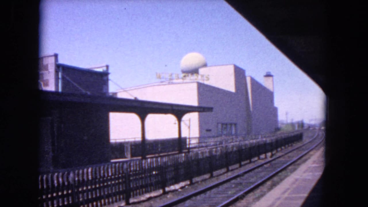 1964 Evanston station platform with empty tracks, canopy, fence, and a dome-topped building marked with Wisconsin signage.