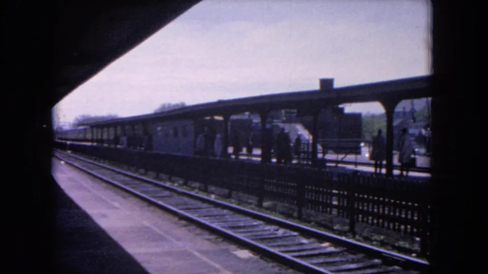 Evanston rail platform in 1964 with tracks, canopy, waiting passengers, and a train visible across the platform.