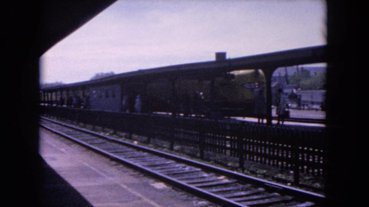 The arriving train moves along the Evanston platform while passengers stand beneath the covered shelter.