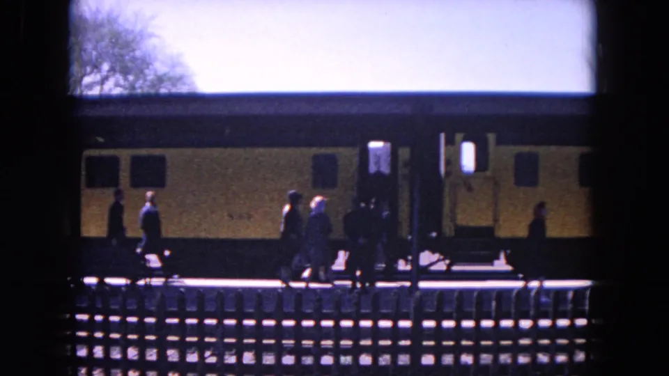 Home-movie view of passengers crossing the platform in front of a yellow-and-black train in Evanston, Illinois, in 1964.