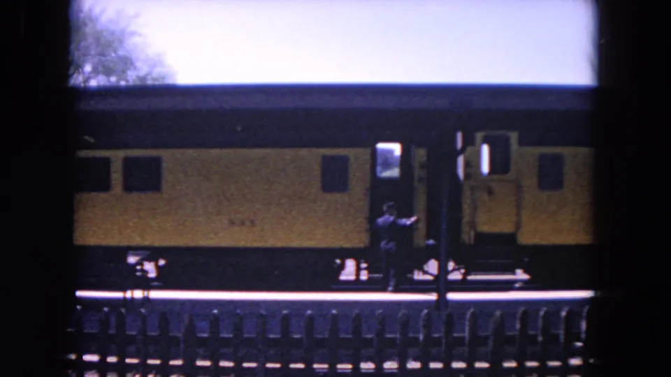 Late frame of the 1964 Evanston station scene, with the train doors open and only a few passengers visible near the platform edge.