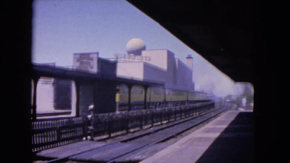 Final 1964 Evanston frame shows the train farther along the platform, tracks leading into the distance, and a domed building with visible signage in the background.