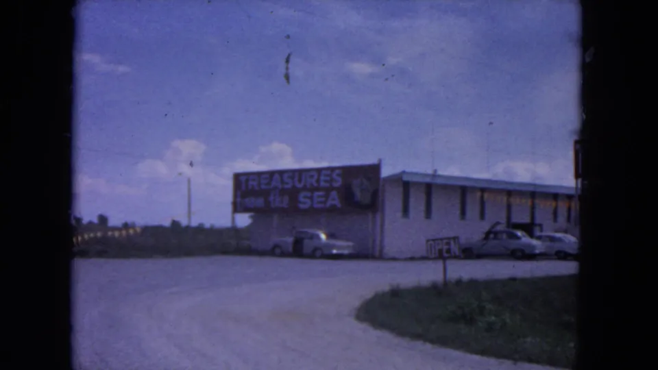 1964 Evanston roadside view showing the Treasure City building with a Treasures from the Sea sign and classic cars parked outside.
