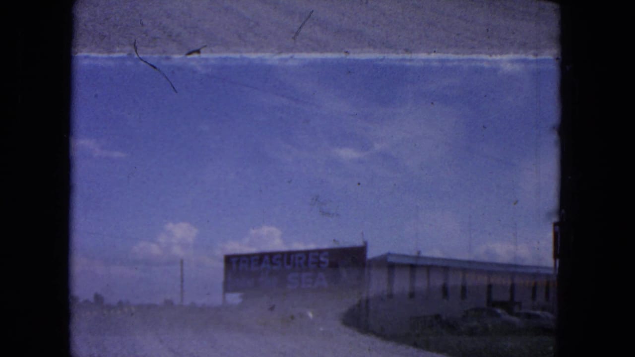 Soft 8mm frame of the Treasure City roadside building in Evanston, with the Treasures from the Sea sign partly legible.