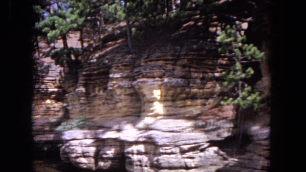 Layered rock bluff with trees above, seen from a boat on the river.