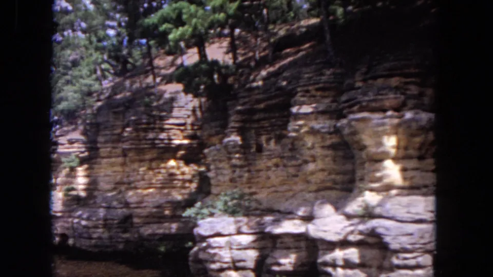 A moving 8mm river view shows layered stone, shaded trees, and water along the Evanston, Illinois shoreline.