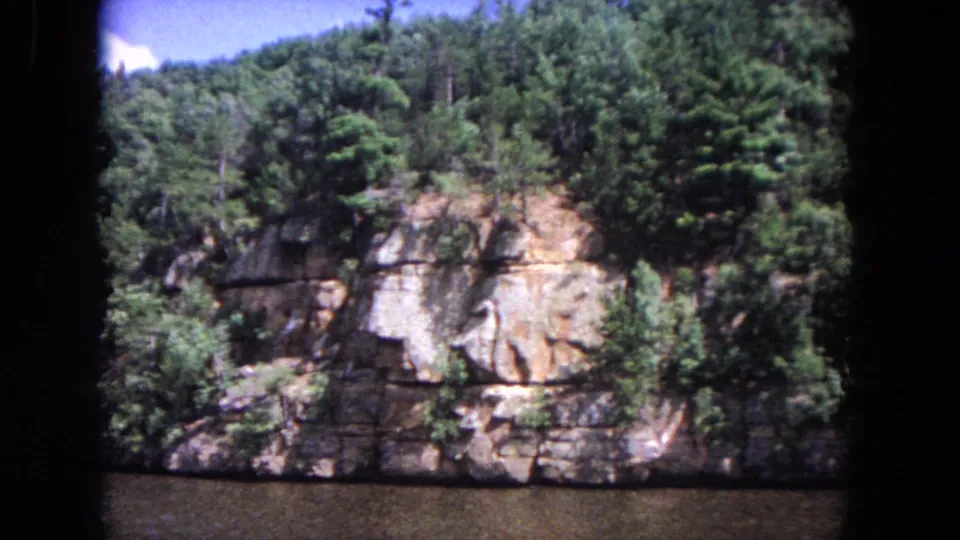 A final 1964 8mm view holds on a wooded cliff face and calm river, cataloged to Evanston, Illinois.