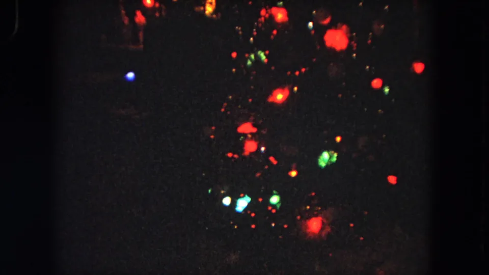 1964 Evanston 8mm frame with blurred colored lights flickering in darkness, likely a night display or decorative illumination.
