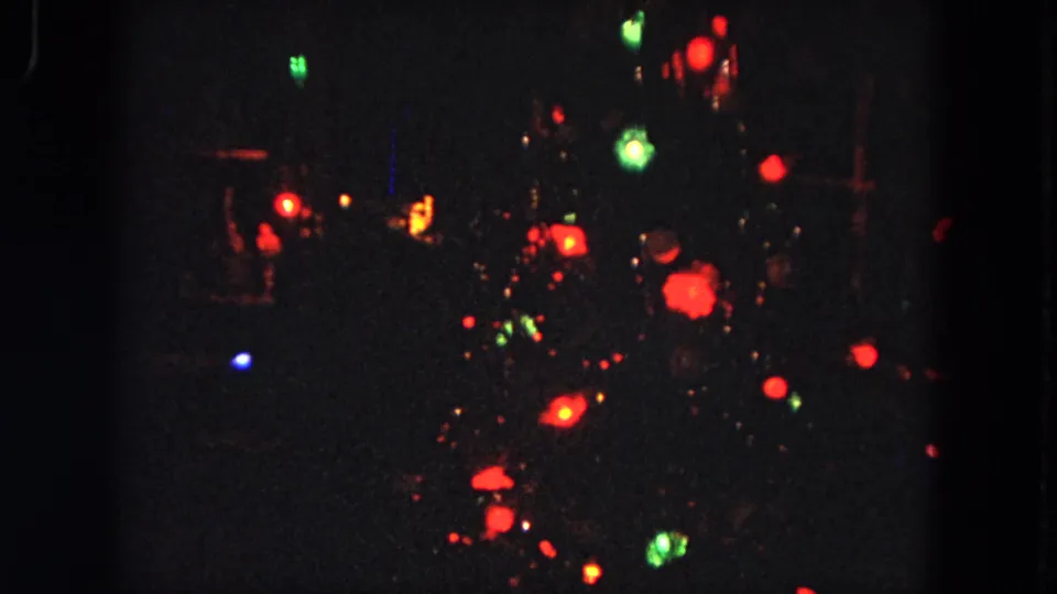 Evanston 1964 8mm frame with red, green, and blue lights blooming softly against a black night background.