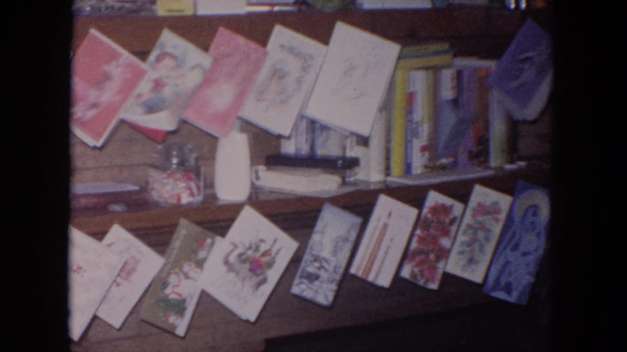 Christmas cards arranged along a wooden mantel with books and a candy jar behind them.