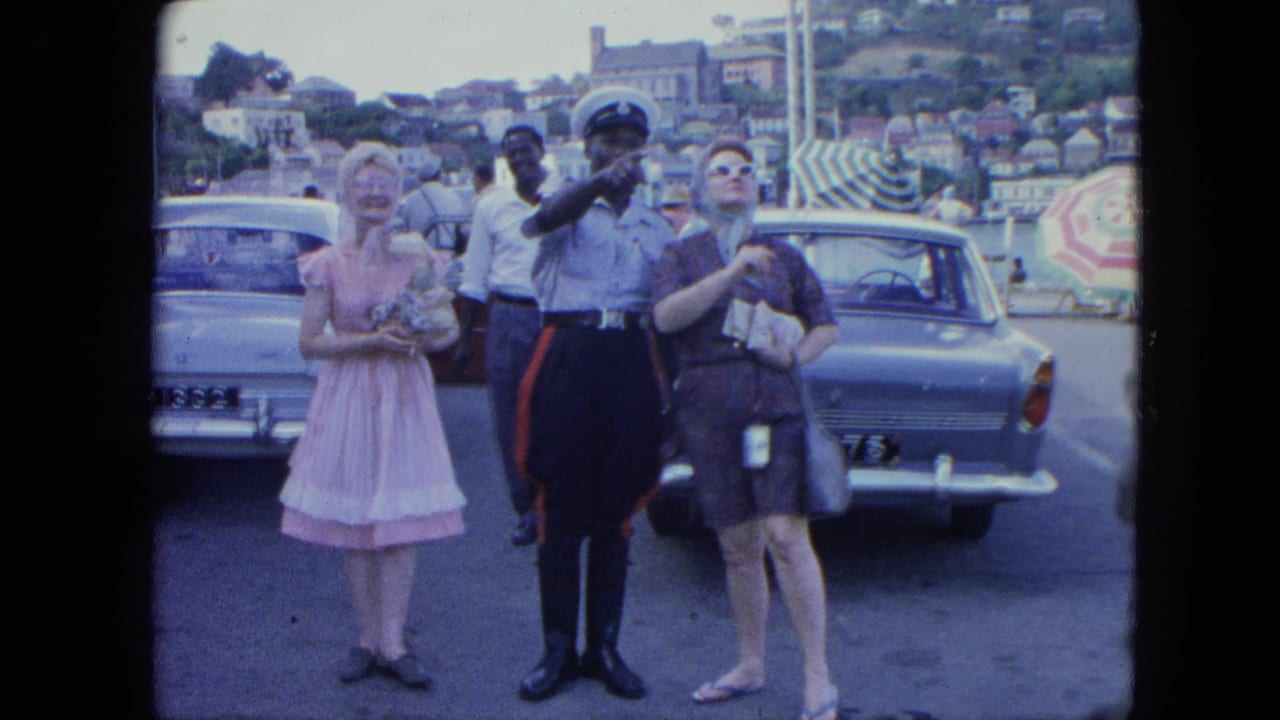 Two women stand with a police officer as he points across a parking lot.