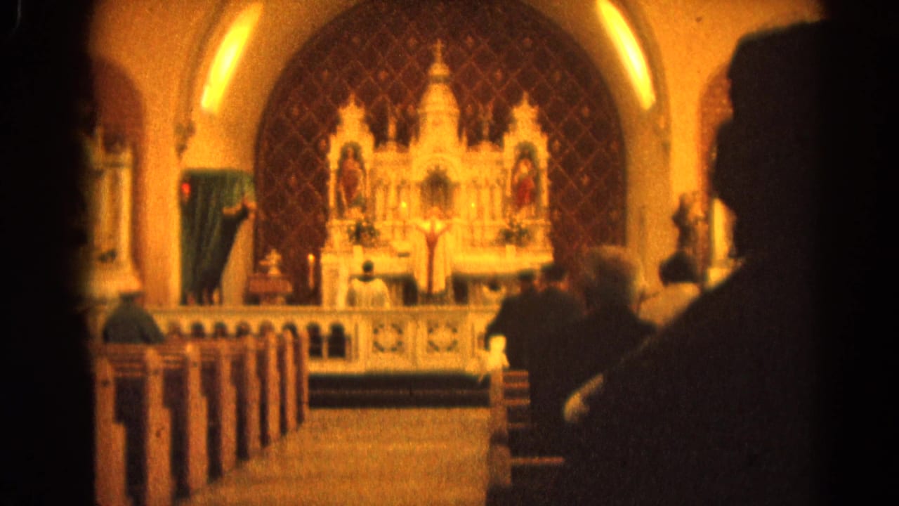 Church pews and altar seen past dark foreground silhouettes.